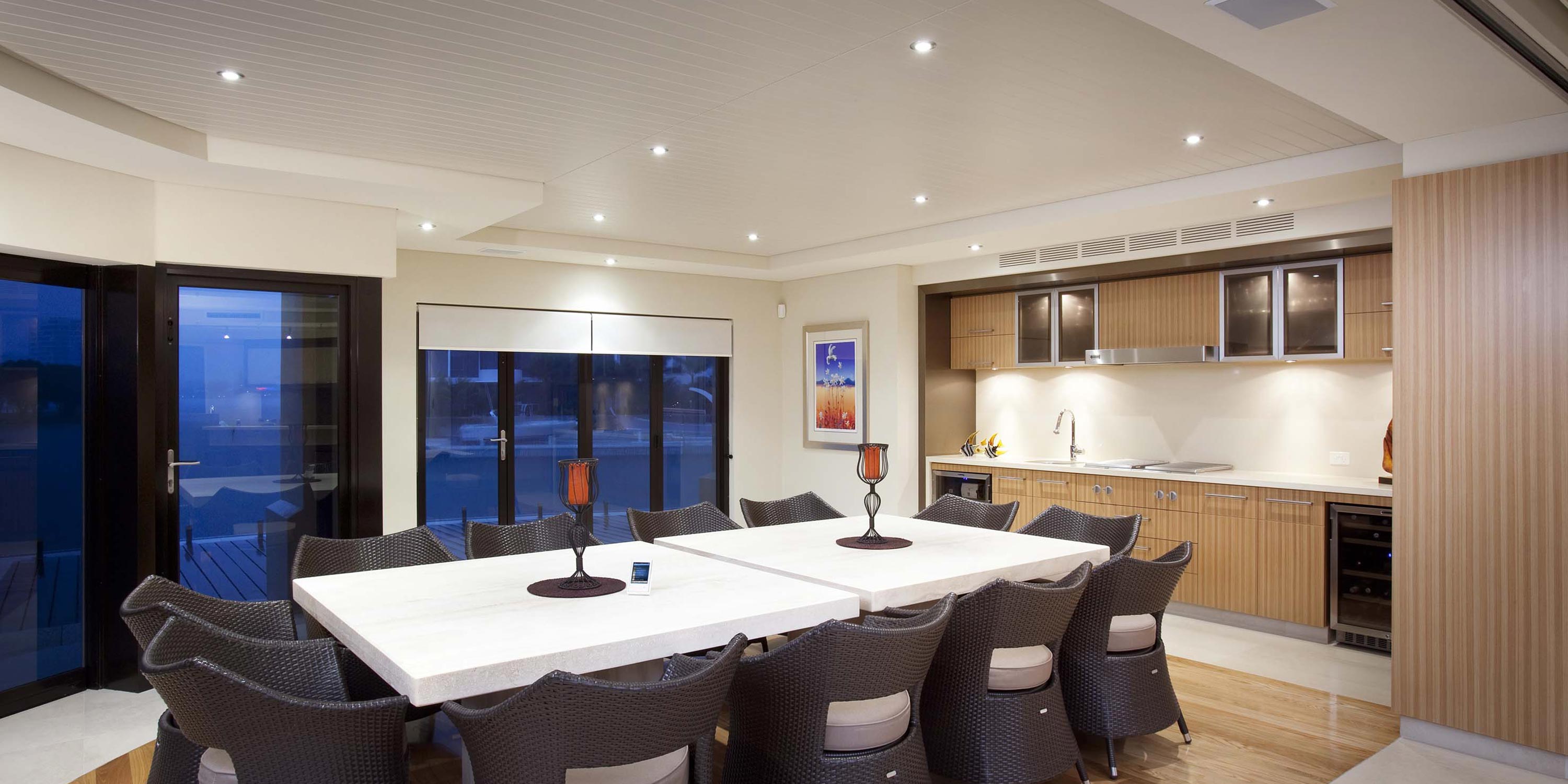 Modern dining area with a long table and wicker chairs.