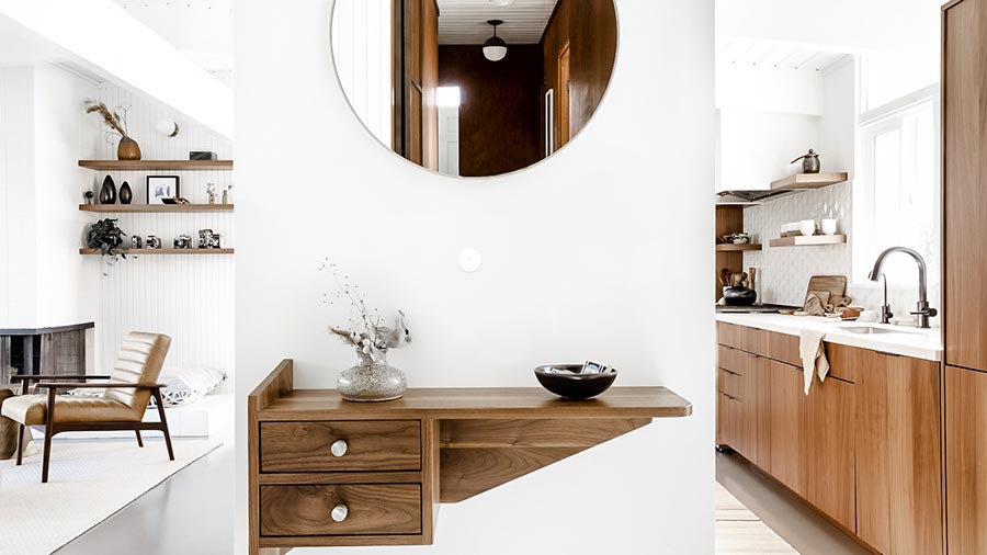 Bright entryway with a wooden floating console, round mirror, and warm interior details.
