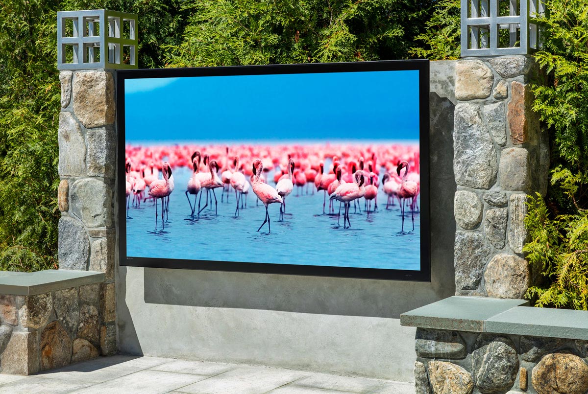 Outdoor TV mounted between stone pillars displaying a vibrant flamingo scene.
