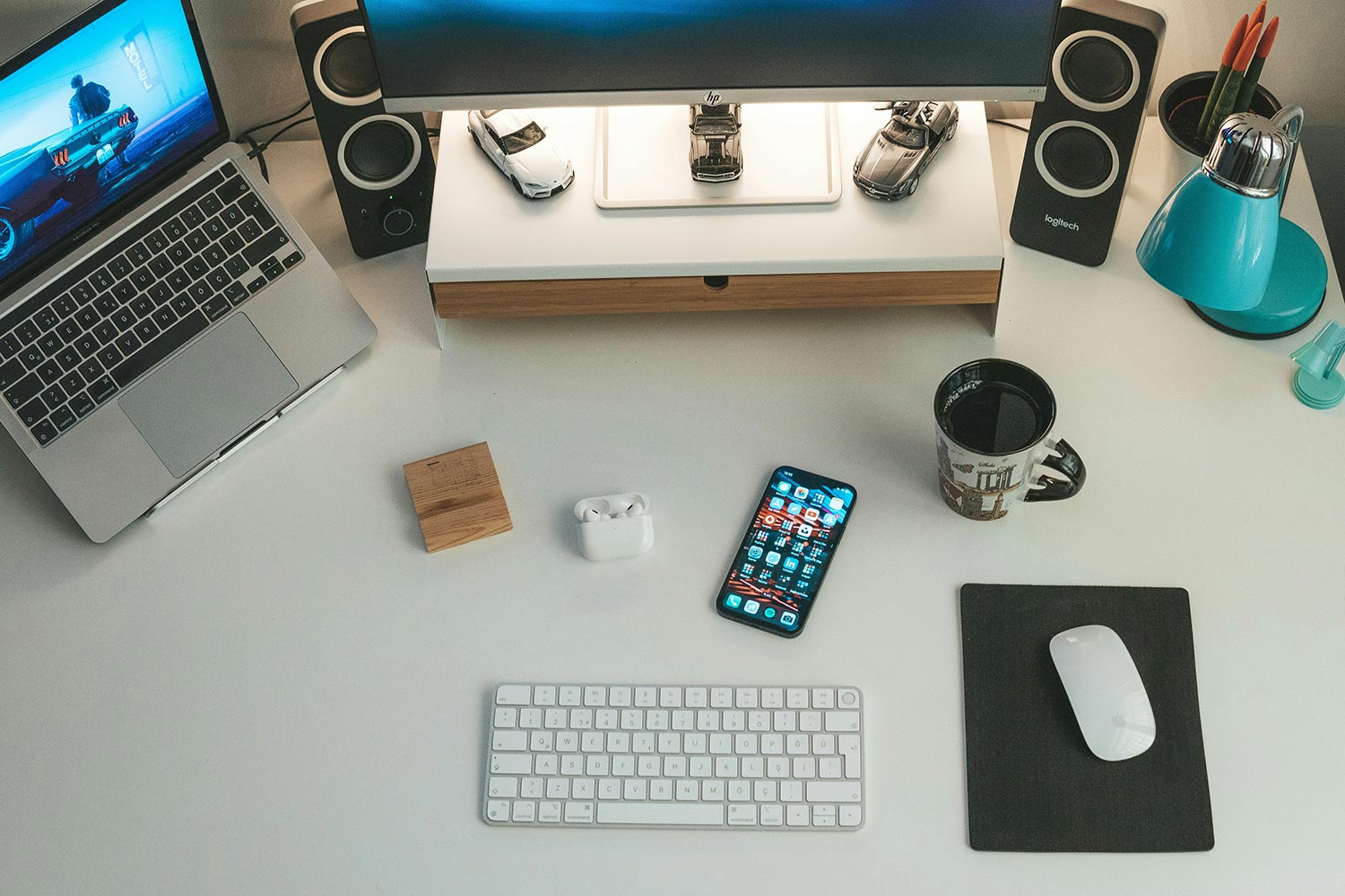 Overhead view of tech desk with laptop, speakers, phone, and accessories