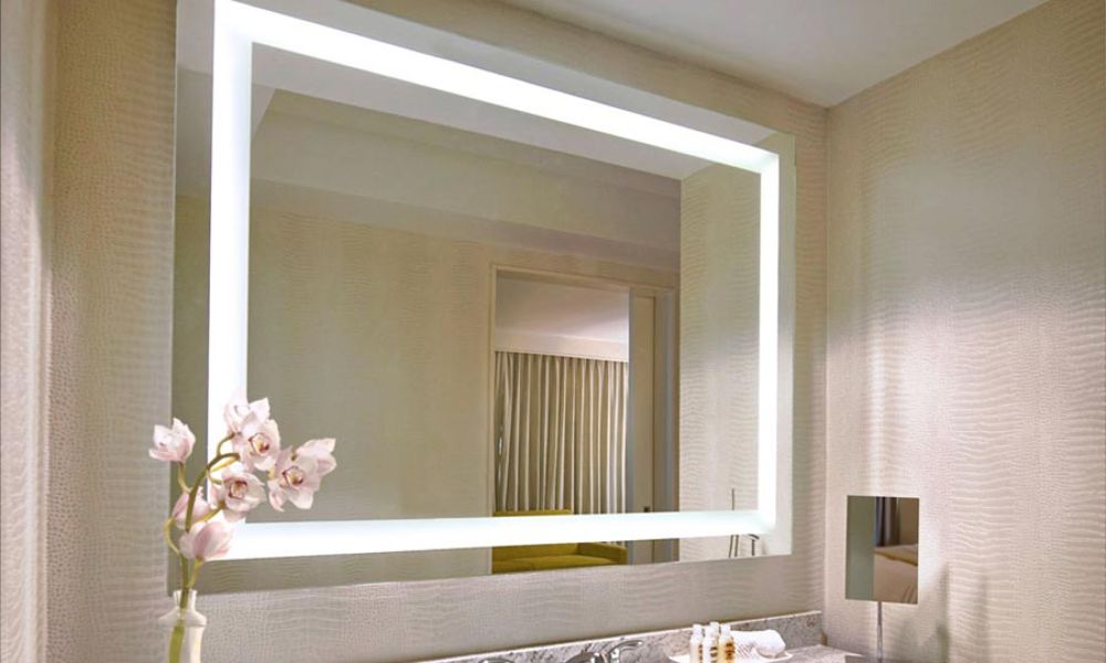 Modern bathroom with a backlit mirror reflecting a softly lit interior.