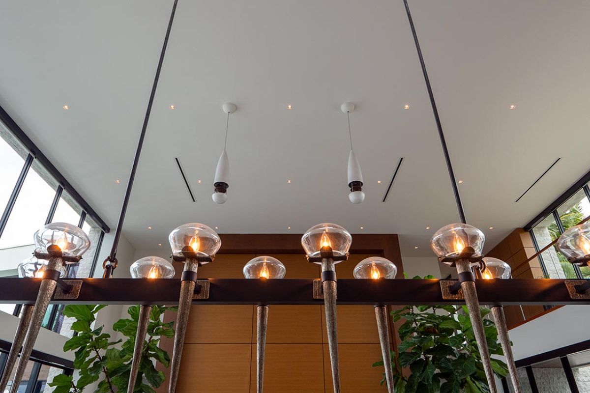 Large modern chandelier hanging in spacious living room with tall windows