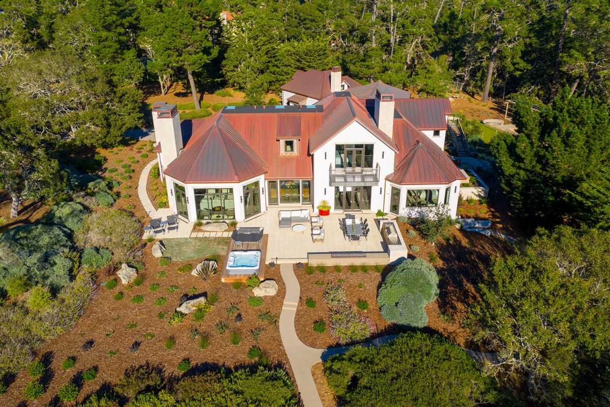 Large modern home with red metal roofing surrounded by trees