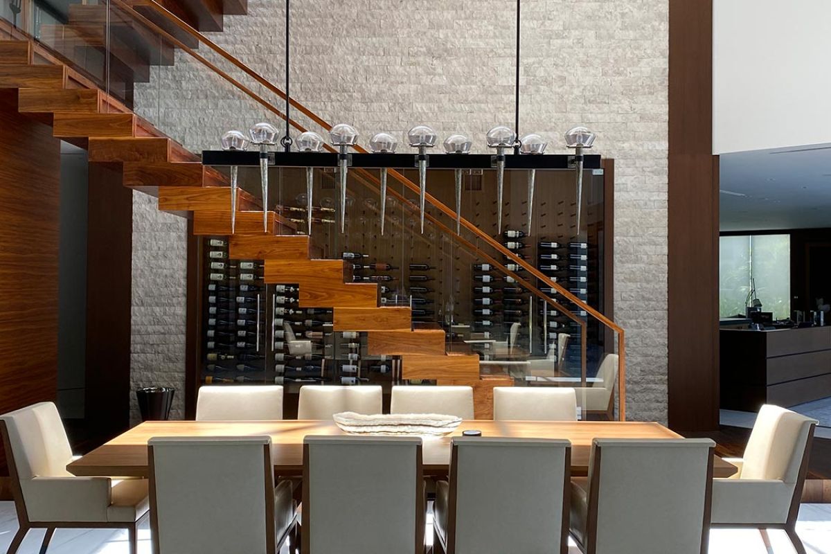 Dining area with modern table and chairs beneath floating staircase