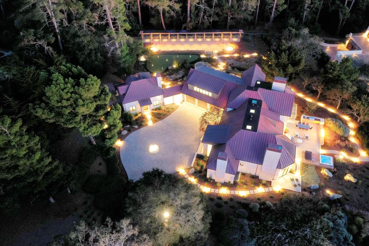 Nighttime view of house exterior and outdoor amenities illuminated