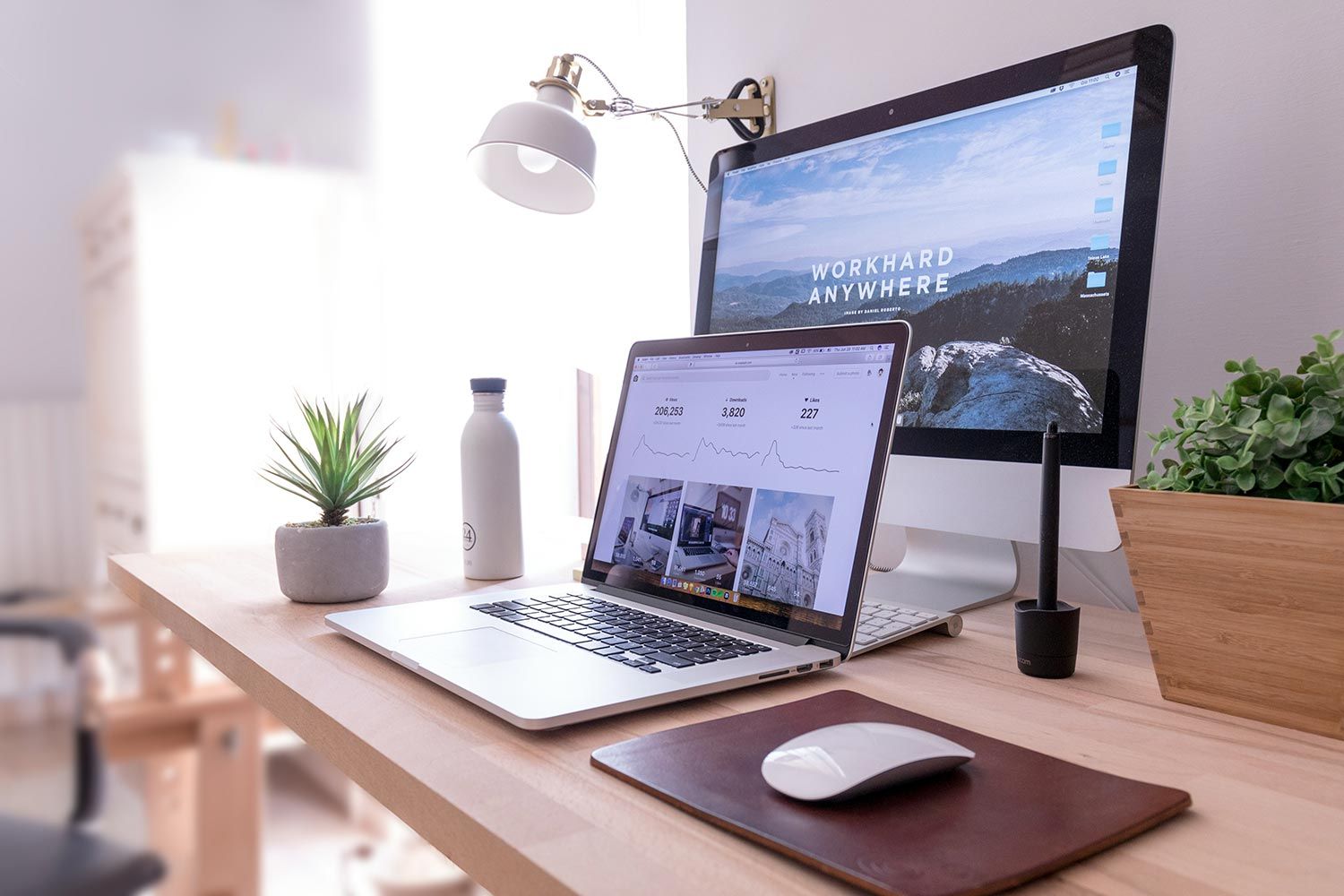 Minimal home office setup with laptop and monitor displaying productivity apps