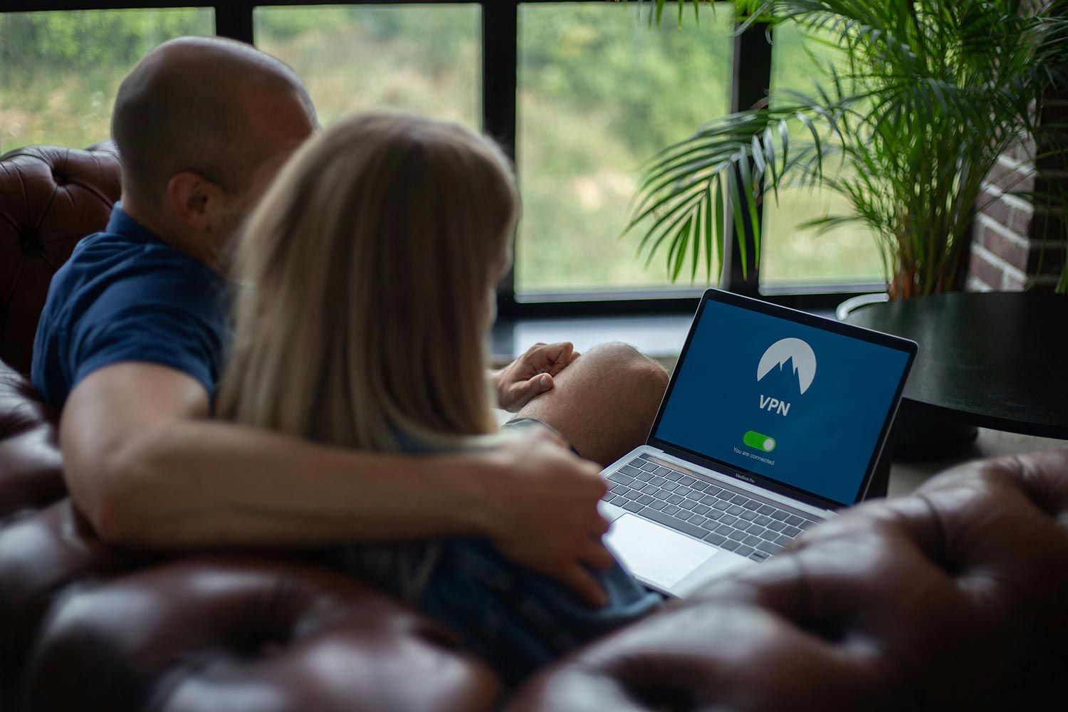 Couple sitting on couch using VPN on laptop for secure internet browsing