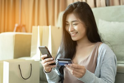 girl smiling at a phone as well as holding a card