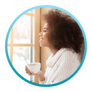 woman looking out the window while drinking tea